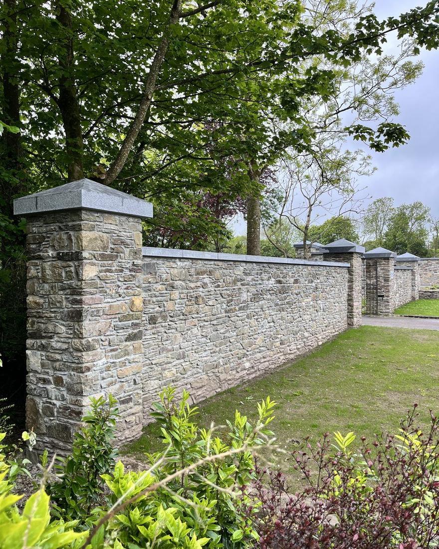 Finished natural stone boundary wall with granite capping