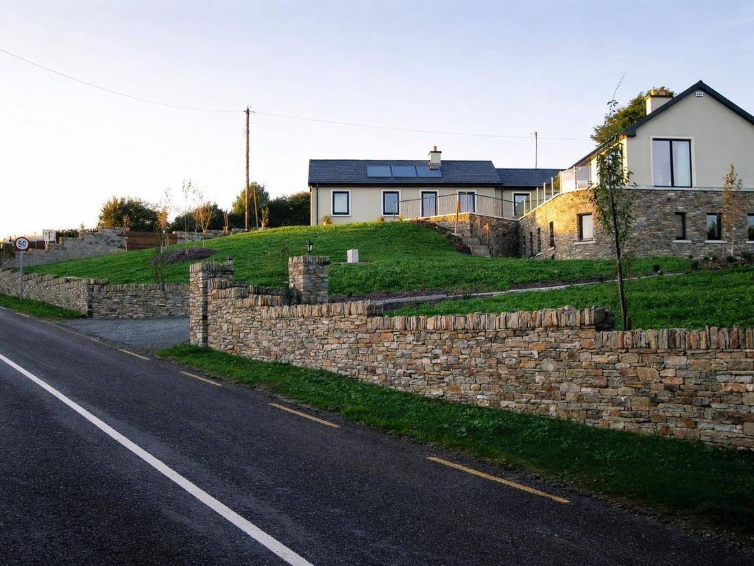 Finished hillside site with dry stone boundary walls and landscaping