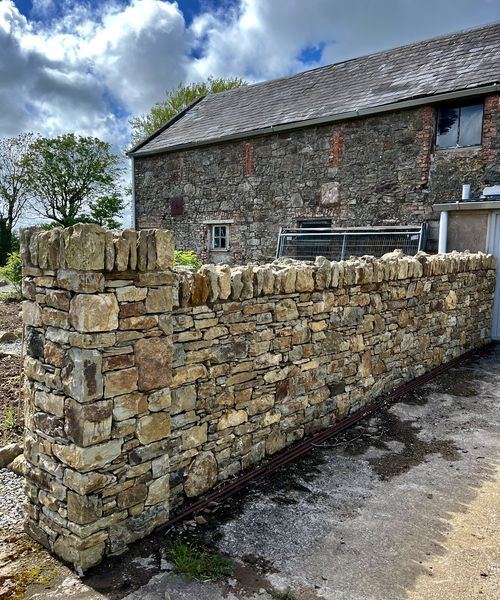 Dry stone sandstone boundary wall with vertical coping