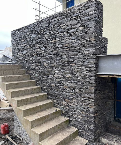 Dark slate feature wall beside concrete staircase