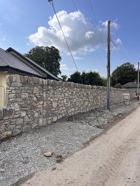 Completed stone boundary wall with coping alongside houses on the Water Rock Road upgrade, Midleton